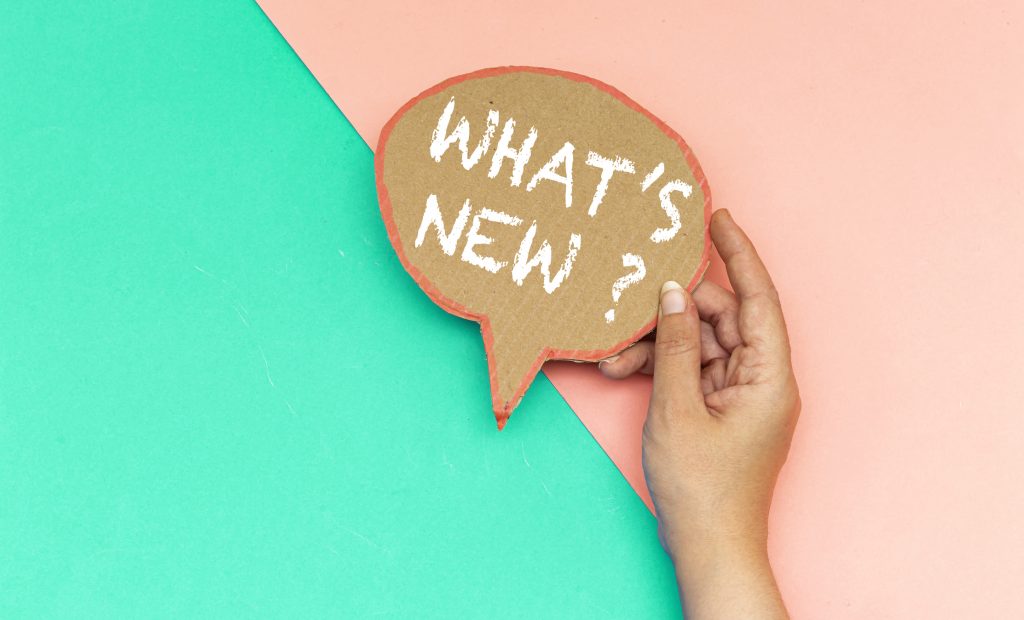 hand holding cardboard sign that asks what's new