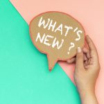 hand holding cardboard sign that asks what's new
